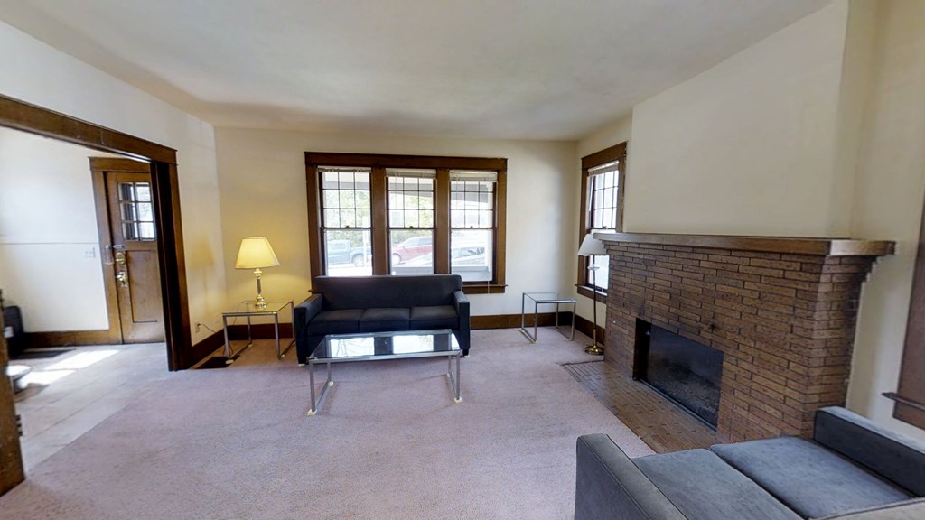 A living room with a black couch and a fireplace.