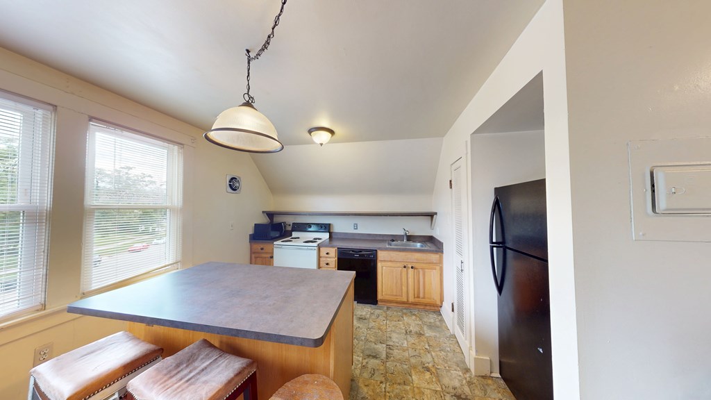 A kitchen with a table and a refrigerator.