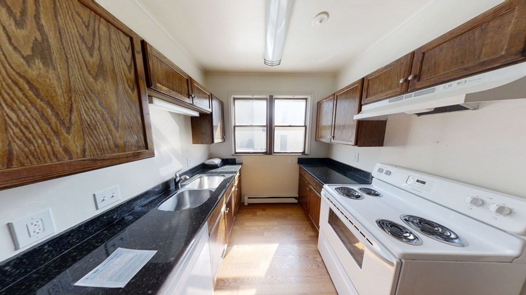 A kitchen with a stove, sink, and cabinets.