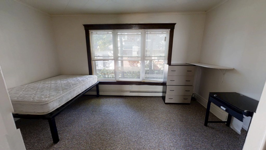 A bedroom with a bed, dresser, and desk.
