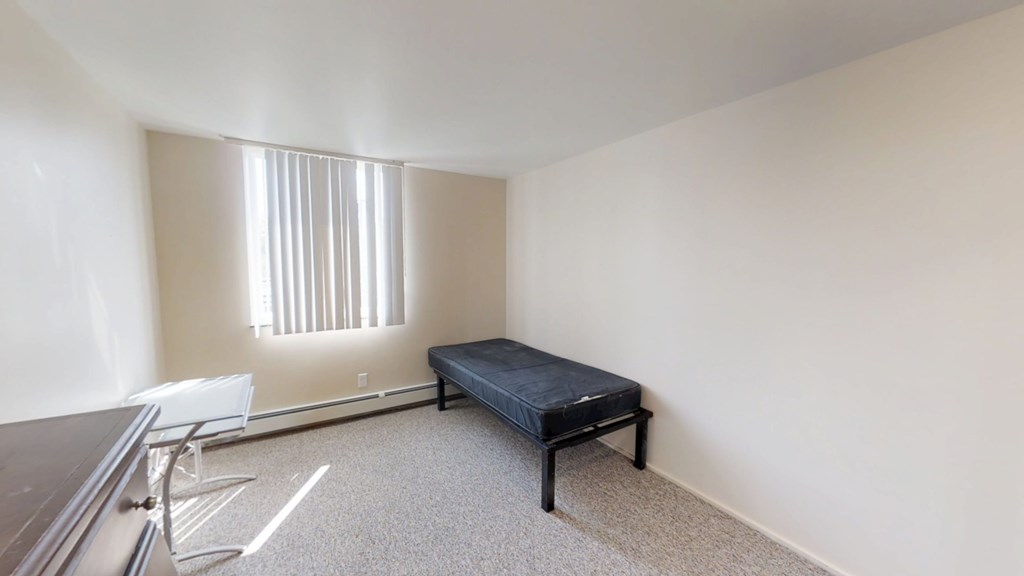 A room with a bed, chair, and window.