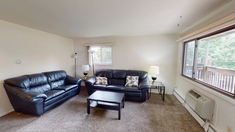 A living room with two black leather couches and a coffee table.