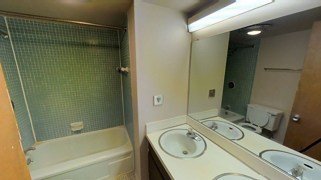 A bathroom with a white bathtub and double sinks.