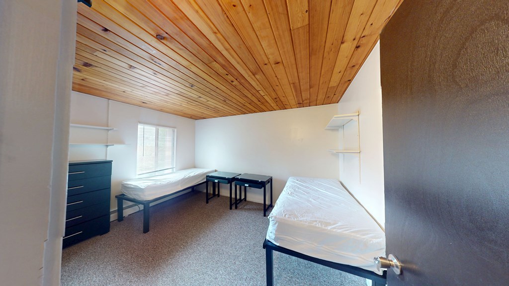 A room with a bed, a table and a dresser.