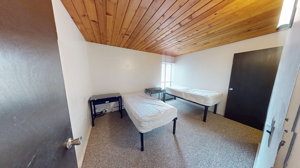 A room with a bed, a bench, and a small table.