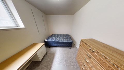 A bedroom with a bed, dresser, and window.
