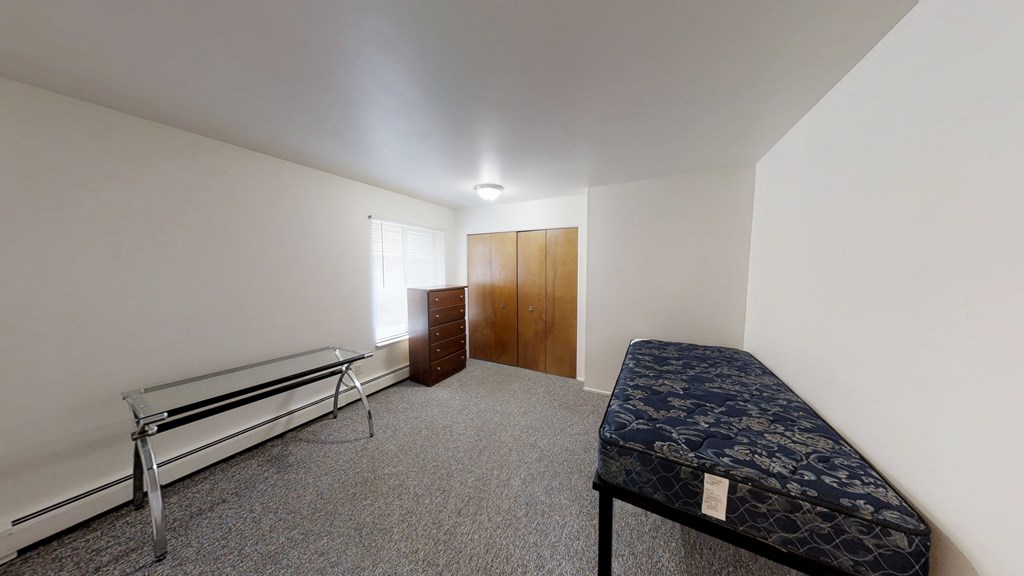 A room with a bed, a bench, and a wardrobe.