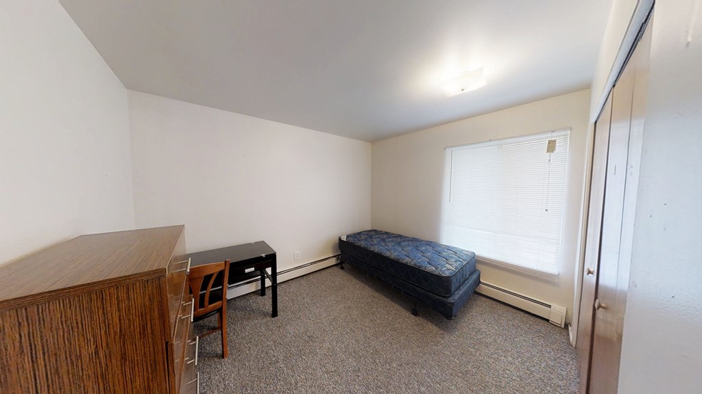 A room with a bed, desk, and chair.