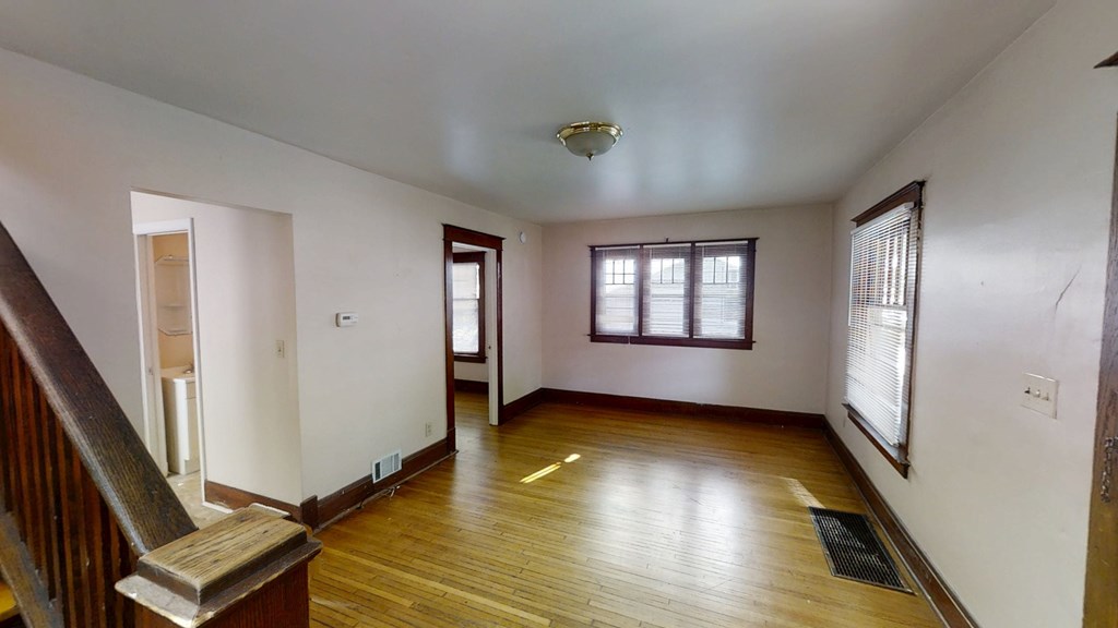 A room with wooden floors and a staircase leading to another room.