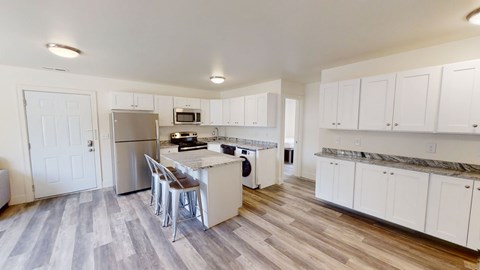 A kitchen with white cabinets and a wooden floor.