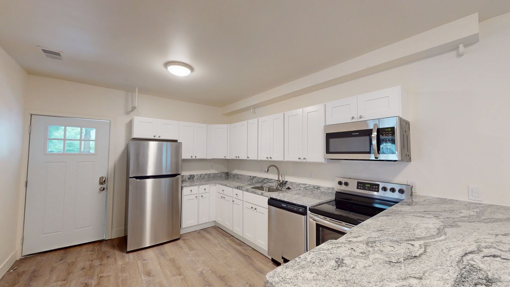 A kitchen with white cabinets and a granite countertop.
