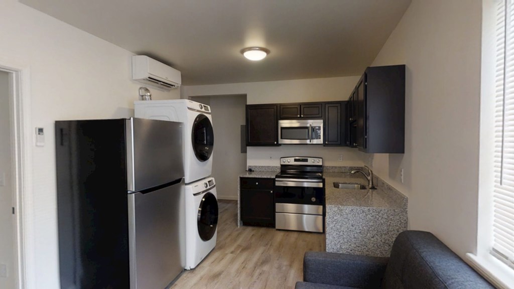 A modern kitchen with a refrigerator, microwave, and oven.