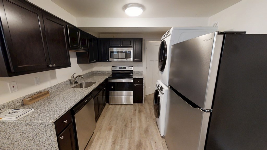 A kitchen with a black fridge and black cabinets.