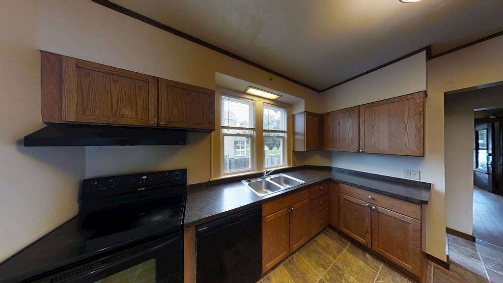 A kitchen with black appliances and wooden cabinets.