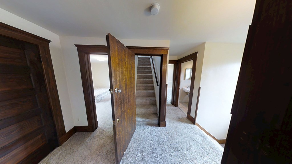 A room with a carpeted floor and a wooden door.
