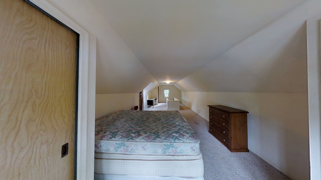 A bedroom with a bed, dresser, and mirror.