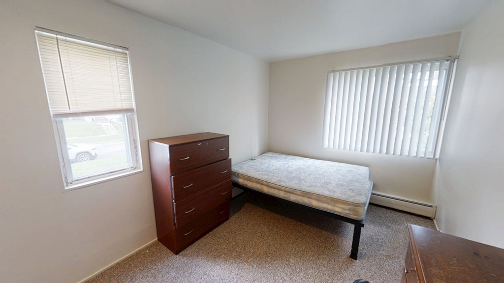 A bedroom with a bed, dresser, and window.
