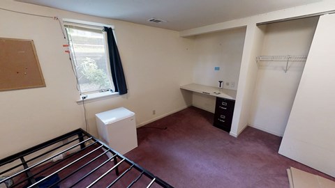 A room with a window, a radiator, and a white cabinet.