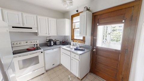 A white kitchen with a stove, oven, and sink.