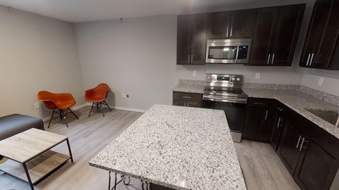 A kitchen with a granite countertop and a dining table with chairs.