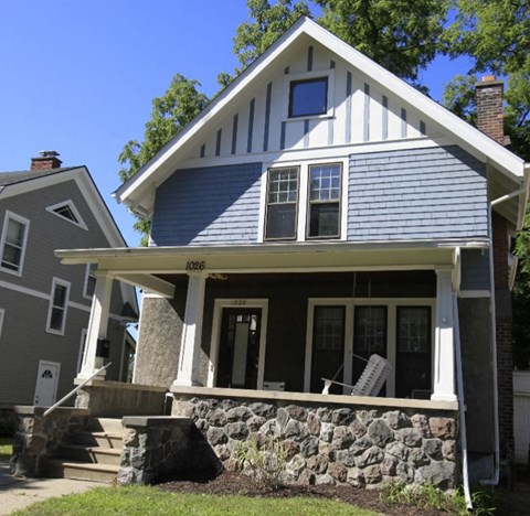 A house with a porch and a stone wall.