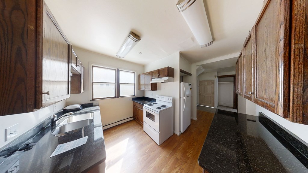 A kitchen with white appliances and wooden cabinets.