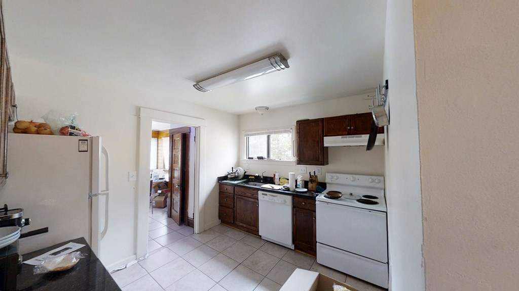 A kitchen with white appliances and a black counter.