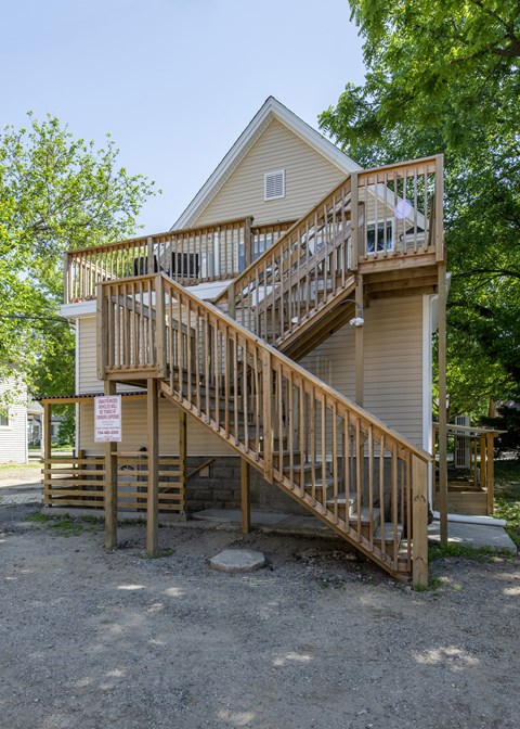 A house with a wooden deck and stairs leading to the second floor.