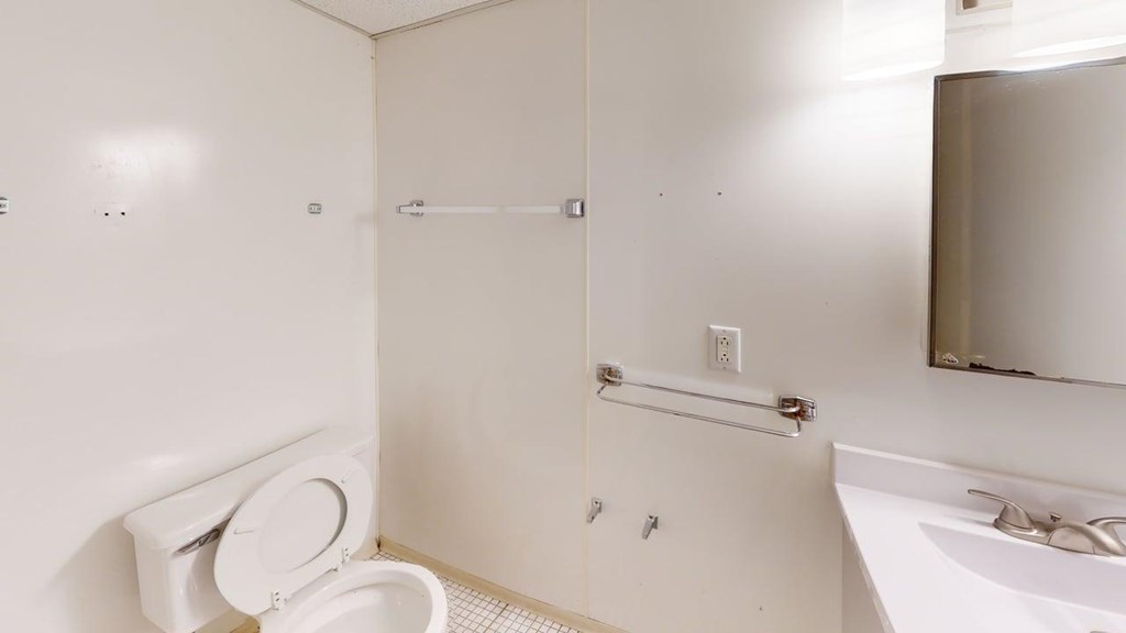 A white bathroom with a toilet, sink, and mirror.
