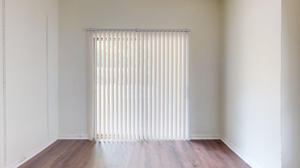 A room with a window covered by a white blind.