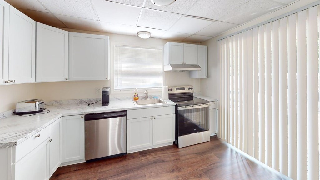 A kitchen with white cabinets and a wooden floor.
