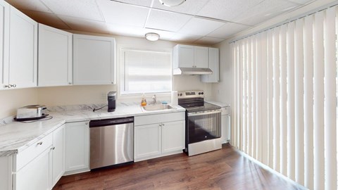 A kitchen with white cabinets and a wooden floor.