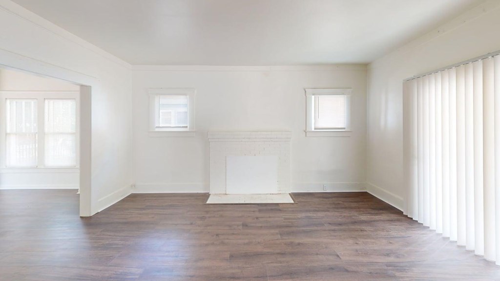 A large, empty room with wooden floors and white walls.