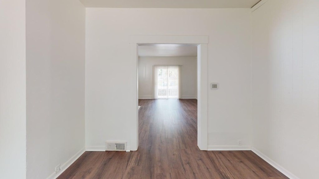 A long, empty room with wooden floors and white walls.