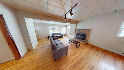 A living room with a grey couch and a wooden floor.