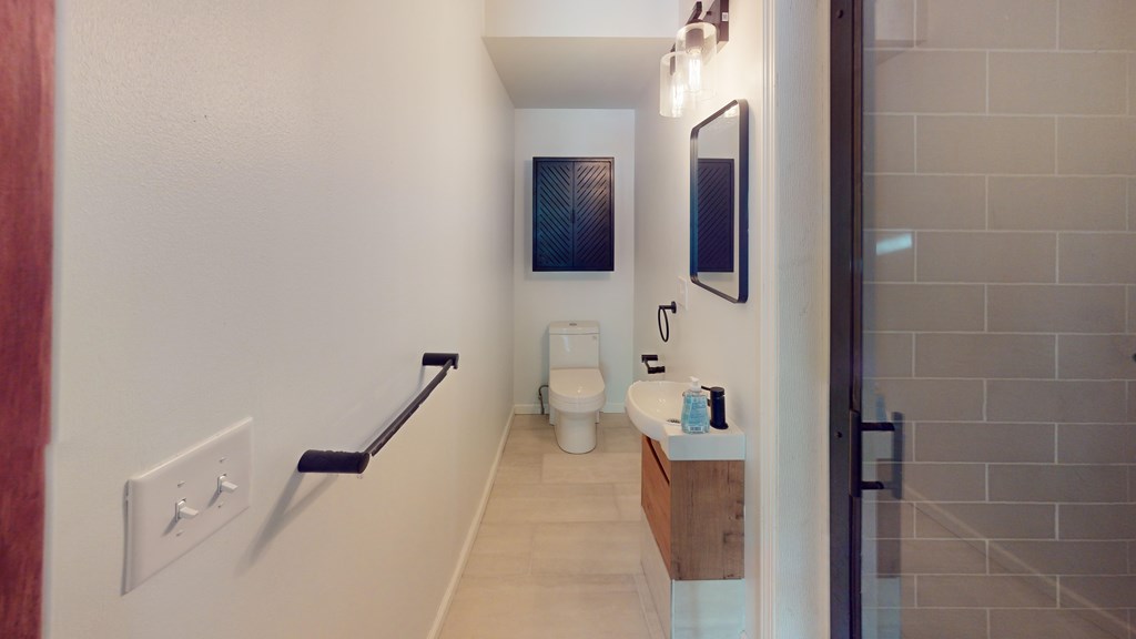 A bathroom with a toilet, sink, and mirror.
