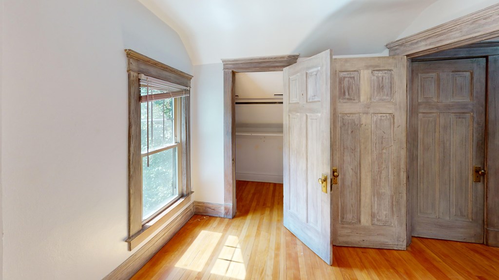 A room with a window and wooden floors.