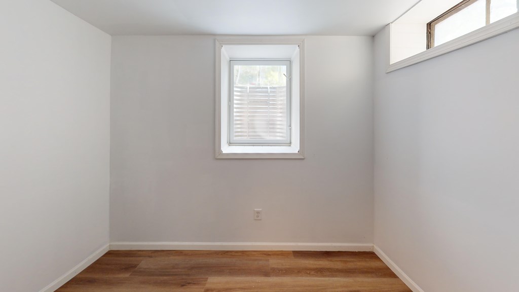 A room with a window and wooden flooring.