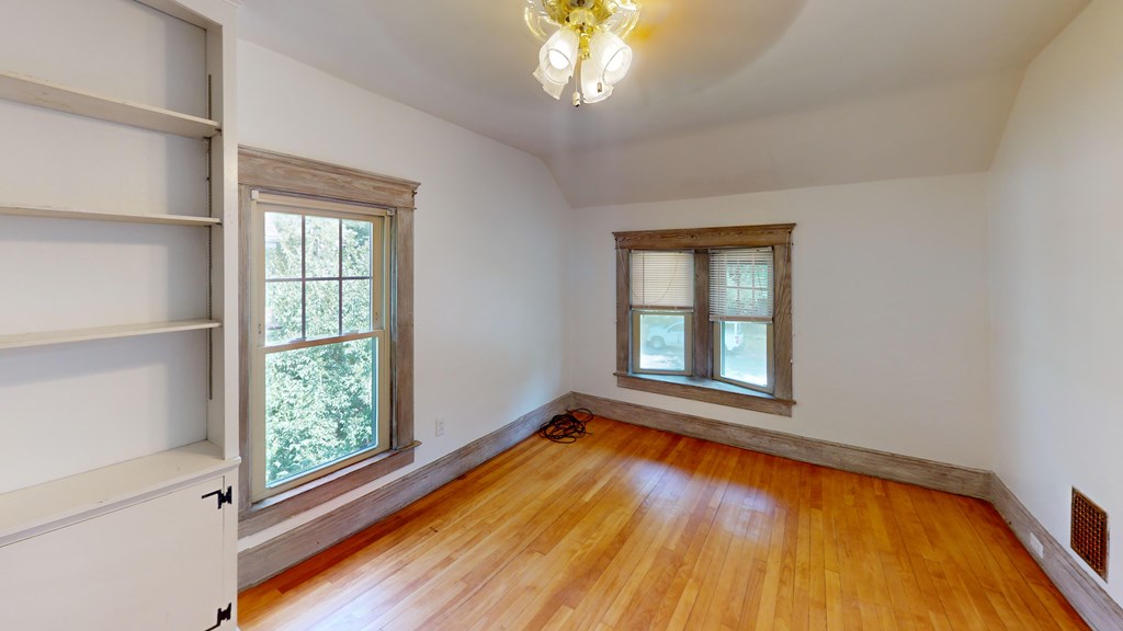 A room with wooden floors and two windows.