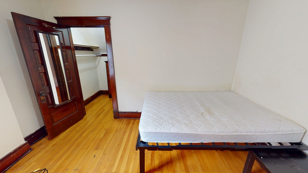 A bed with a mattress and a wooden wardrobe in a room.