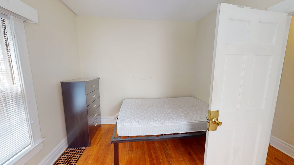 A bedroom with a bed, dresser, and window.