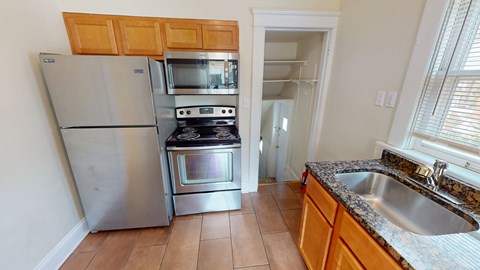 A kitchen with a stove, oven, refrigerator, and sink.