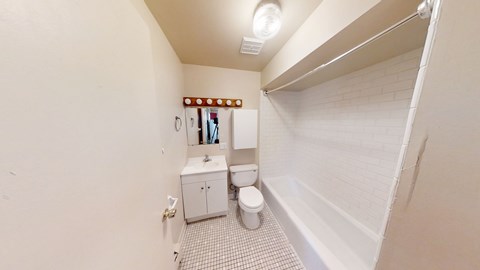 A small bathroom with a toilet, sink, and a mirror.