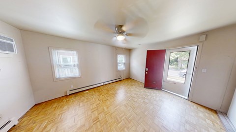 A room with a ceiling fan and wooden flooring.