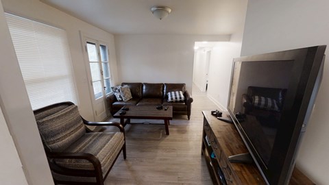 A living room with a couch, chair, and television.