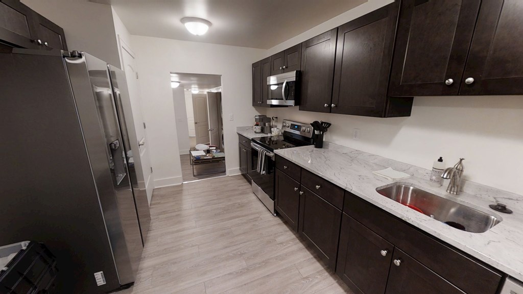 A kitchen with dark wood cabinets and a stainless steel refrigerator.