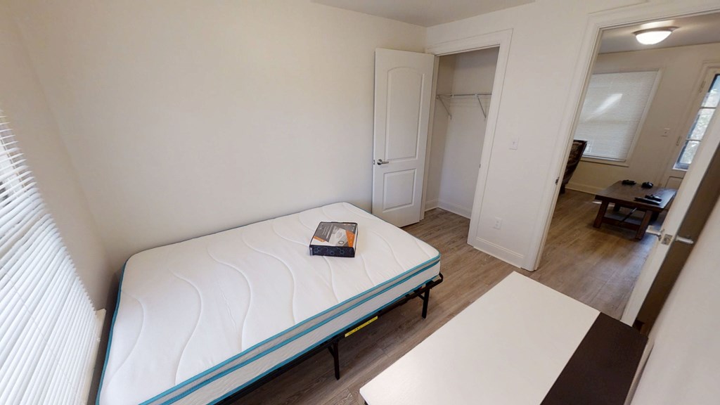A bed with a blue line on it is in a room with a white door and a window.