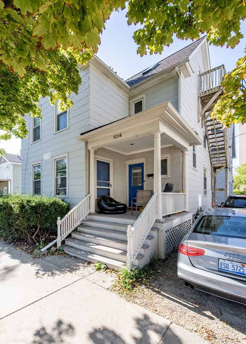 A white house with a blue door and a car parked in front.