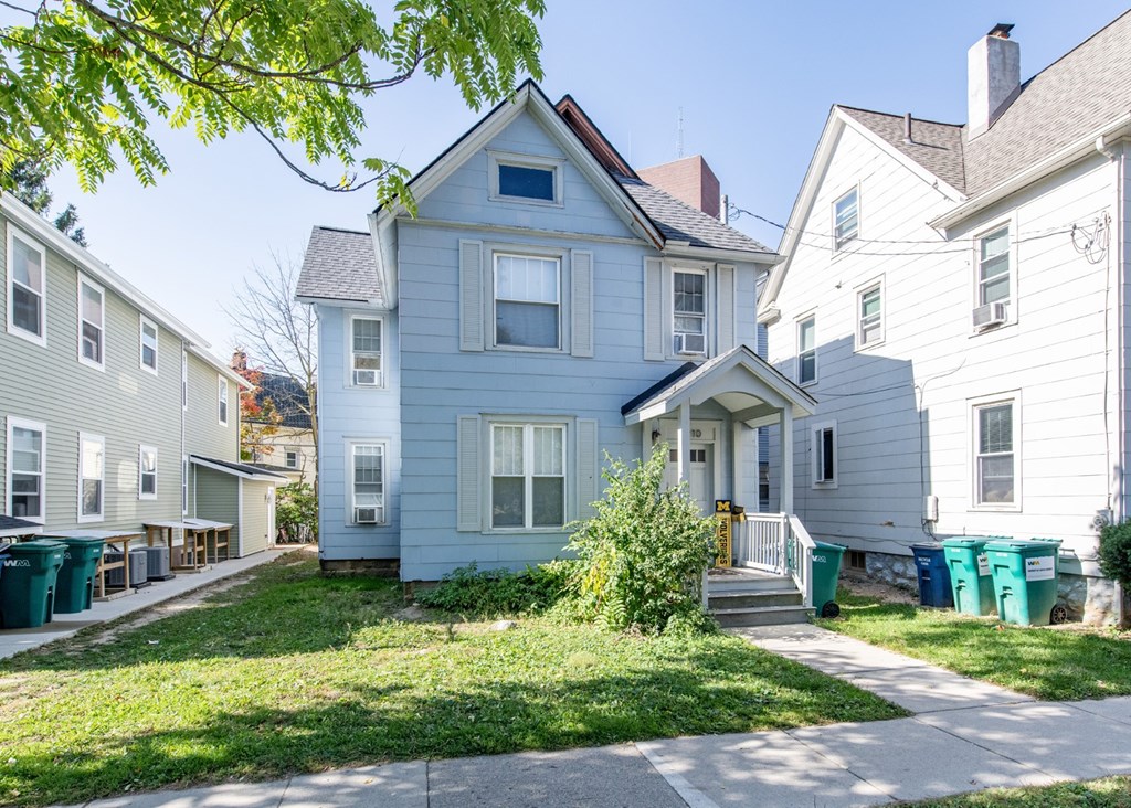 A blue house with a white house behind it.