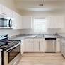 A kitchen with white cabinets and a black counter top.